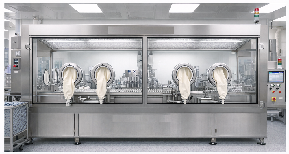 Photograph of a pharmaceutical Restricted Access Barrier System showing glove ports, barrier enclosure, and integrated ISO 5 airflow over an aseptic filling operation.