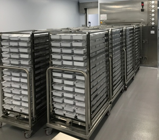 Multiple stainless steel rack carts fully loaded with trays prior to VHP chamber insertion.